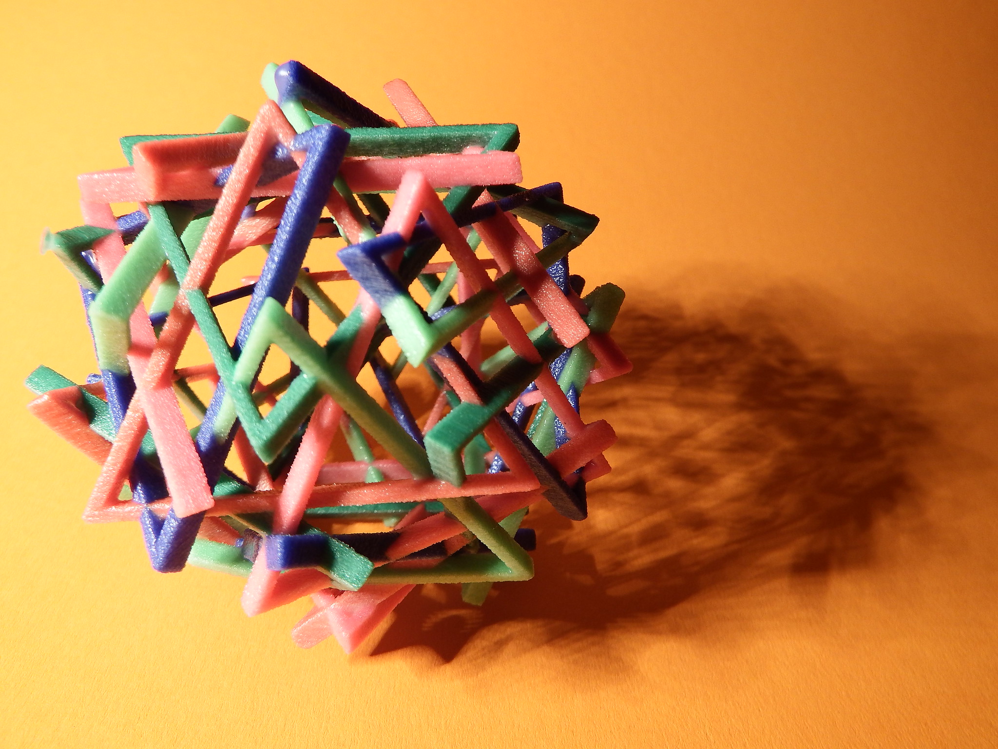 A spherical shaped component made of different individual 3D printed triangles of various colors and materials