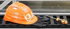 A cable carrier with gloves, a screwdriver, and an igus hardhat on top