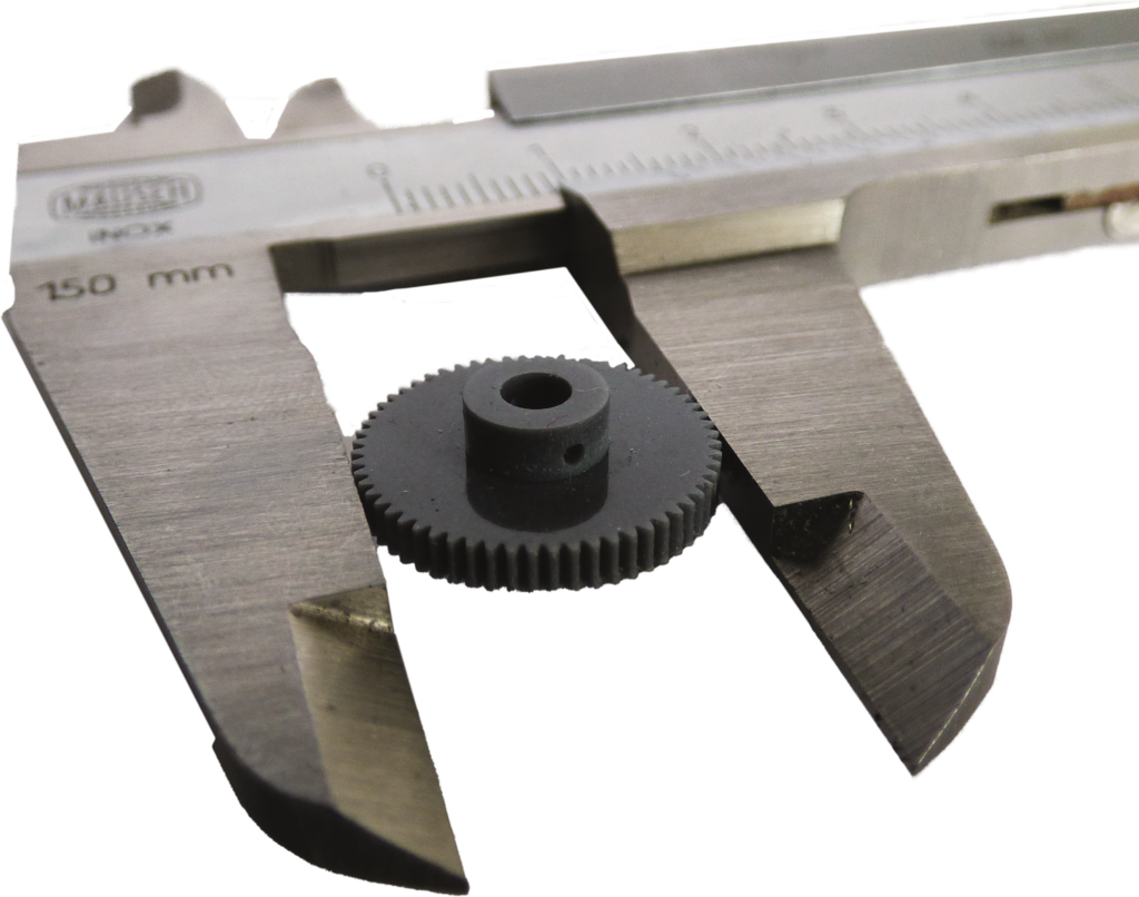 A miniature 3D-printed gear being measured by a caliper